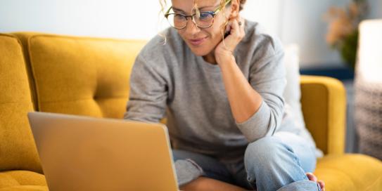 Frau sitzt auf Sofa am Laptop