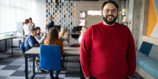 Mann im roten Pulli steht in einem Büro