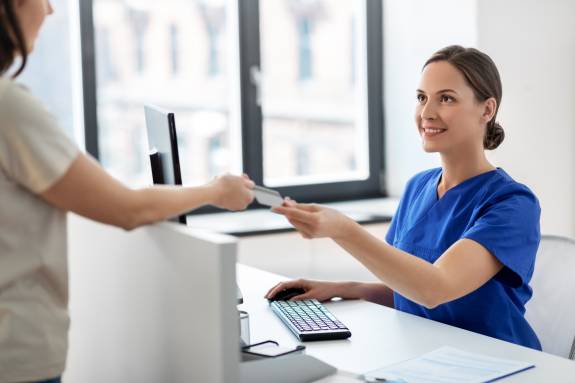 Patientin gibt Krankenshwester Krankenkassenkarte