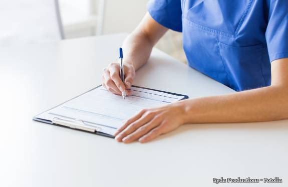 Krankenschwester notiert etwas auf Klemmbrett