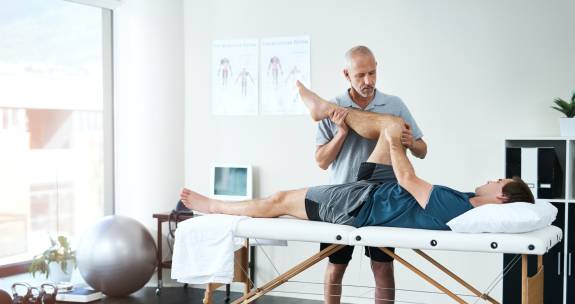 Arzt dehnt das Bein des Patienten