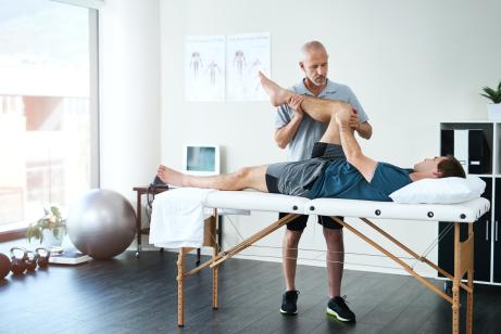 Arzt dehnt das Bein des Patienten